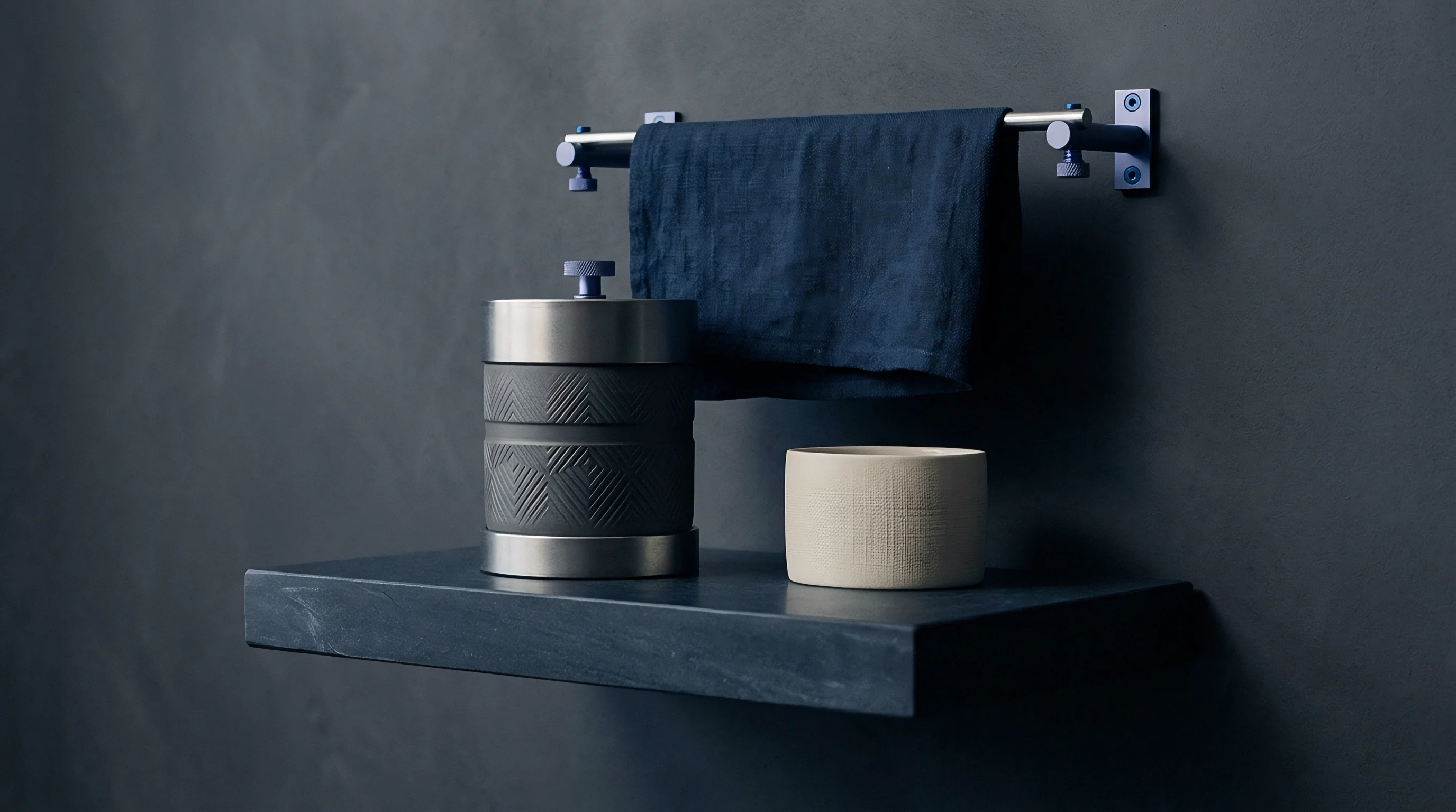 Dark blue woven linen towel hangs over a metallic rail above textured vessels resting on a dark floating shelf.
